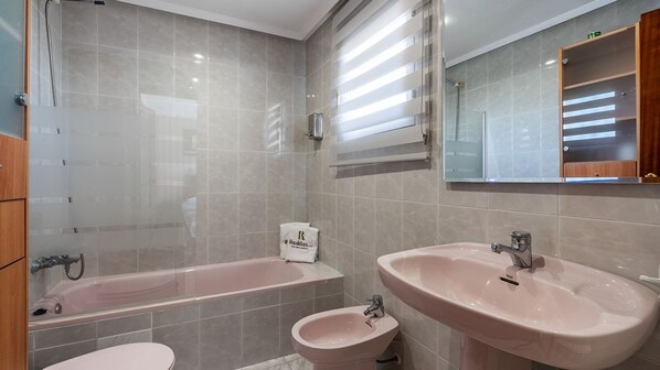 A bathroom with a bathtub, two sinks, a toilet, and a shower.