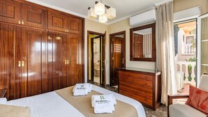 Een hotelkamer met een groot bed, een houten garderobe, een dressoir en een spiegel. Er liggen handdoeken met het logo van het hotel op het bed.