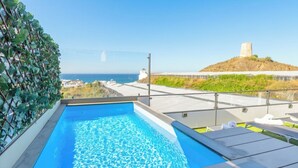 Una piscina al terrat amb una vista clara del mar i una collada amb una torre.