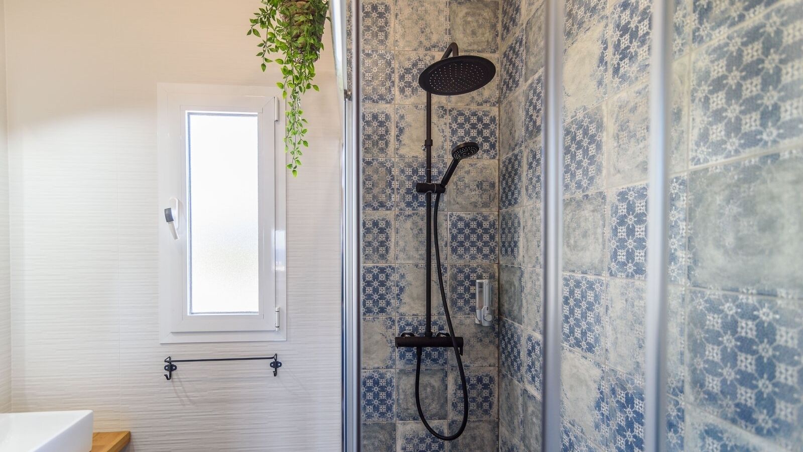 Ein Badezimmer mit Dusche, Fenster und Fliesen mit Muster.