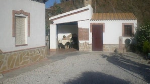 A building with a gravel driveway, a wooden door, and a small window with shutters. - Cortijo el Maurel Cajiz by Ruralidays (Málaga)