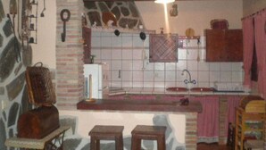A rustic kitchen with stone walls, a tiled backsplash, a wooden countertop, and a sink. - Cortijo el Maurel Cajiz by Ruralidays (Málaga)