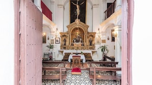 Een kerkinterieur met een houten altaar, banken en een betegelde vloer.