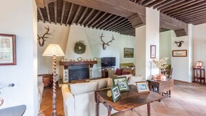 Een gezellige woonkamer met een open haard, een bank, een salontafel met ingekaderde foto's en decoraties van gewei aan de muur.