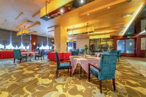 A spacious dining area with multiple tables and chairs, a patterned carpet, and a warm ceiling design. - Yin Sheng International Hotel (Heze)