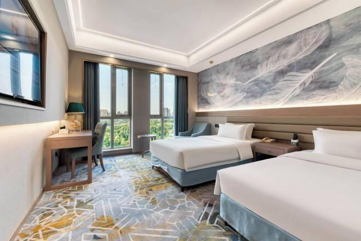 A hotel room with a large bed, a desk, a chair, and a view of the outdoors.