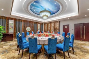 A conference room with a round table, blue chairs, and a chandelier. - Yin Sheng International Hotel (Heze)