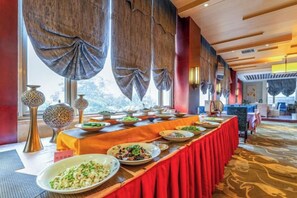 A buffet setup with a long table, various dishes, and a view of the outdoors through large windows. - Yin Sheng International Hotel (Heze)