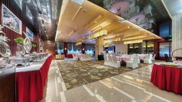 A spacious banquet hall with tables set for events, a high ceiling with lighting fixtures, and a polished floor.