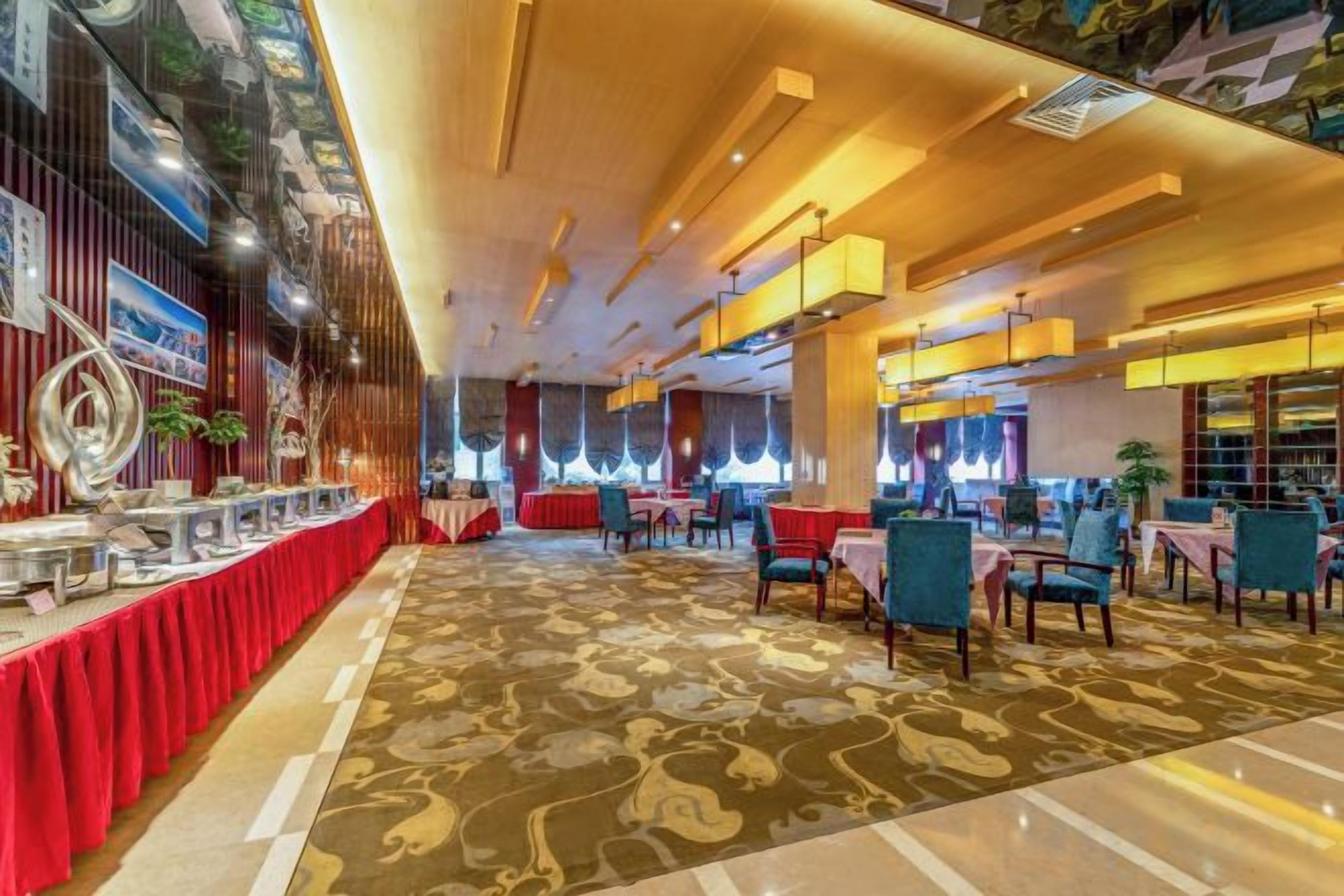 A hotel lobby with a red carpet, a reception desk, and a seating area with tables and chairs.