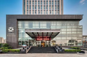 A modern building with a prominent entrance, large glass windows, and a visible staircase leading to the entrance.