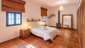 Un dormitorio con cama, mesitas de noche, un espejo, armario y ventana.
