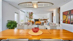 Un salon spacieux avec une grande table à manger en bois, des sièges confortables et un lustre moderne.