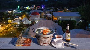 Une table à manger avec un pot de soupe, une assiette de fruits de mer, une bouteille de bière et un bol de sauce.