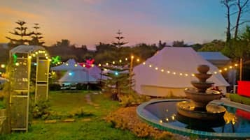 A garden with a fountain, tents, and string lights.