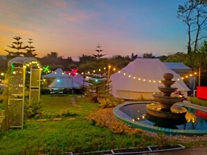 A garden with a fountain, tents, and string lights.