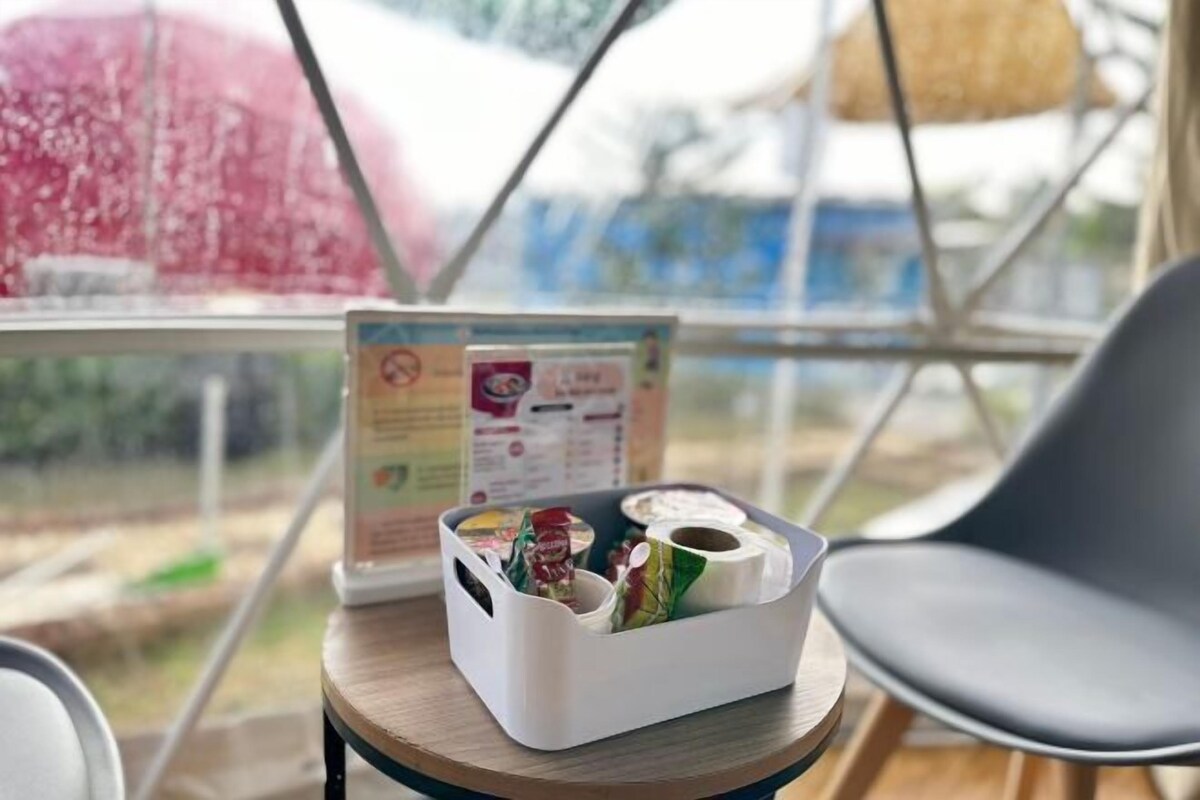 Een tafel met een witte mand met diverse items, een menukaartstandaard en een uitzicht door een raam.