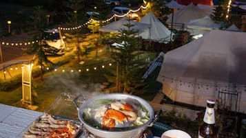 A table with a hot pot, a bottle of beer, and a plate of food.