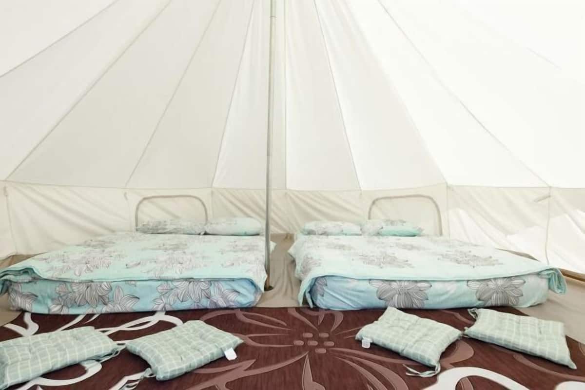 A tent with two beds, each with floral bedding and pillows.