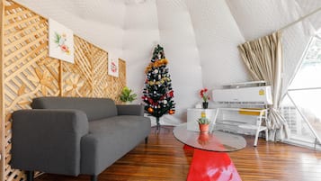 A modern living room with a grey sofa, a small Christmas tree, and a red table.