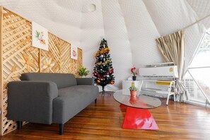 Un salon moderne avec un canapé gris, un petit sapin de Noël et une table rouge.