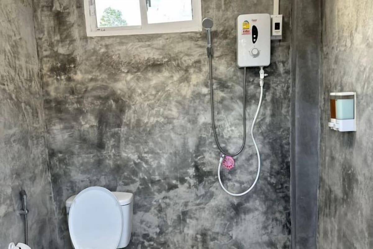 A bathroom with a toilet, a shower with a control panel, and a window.