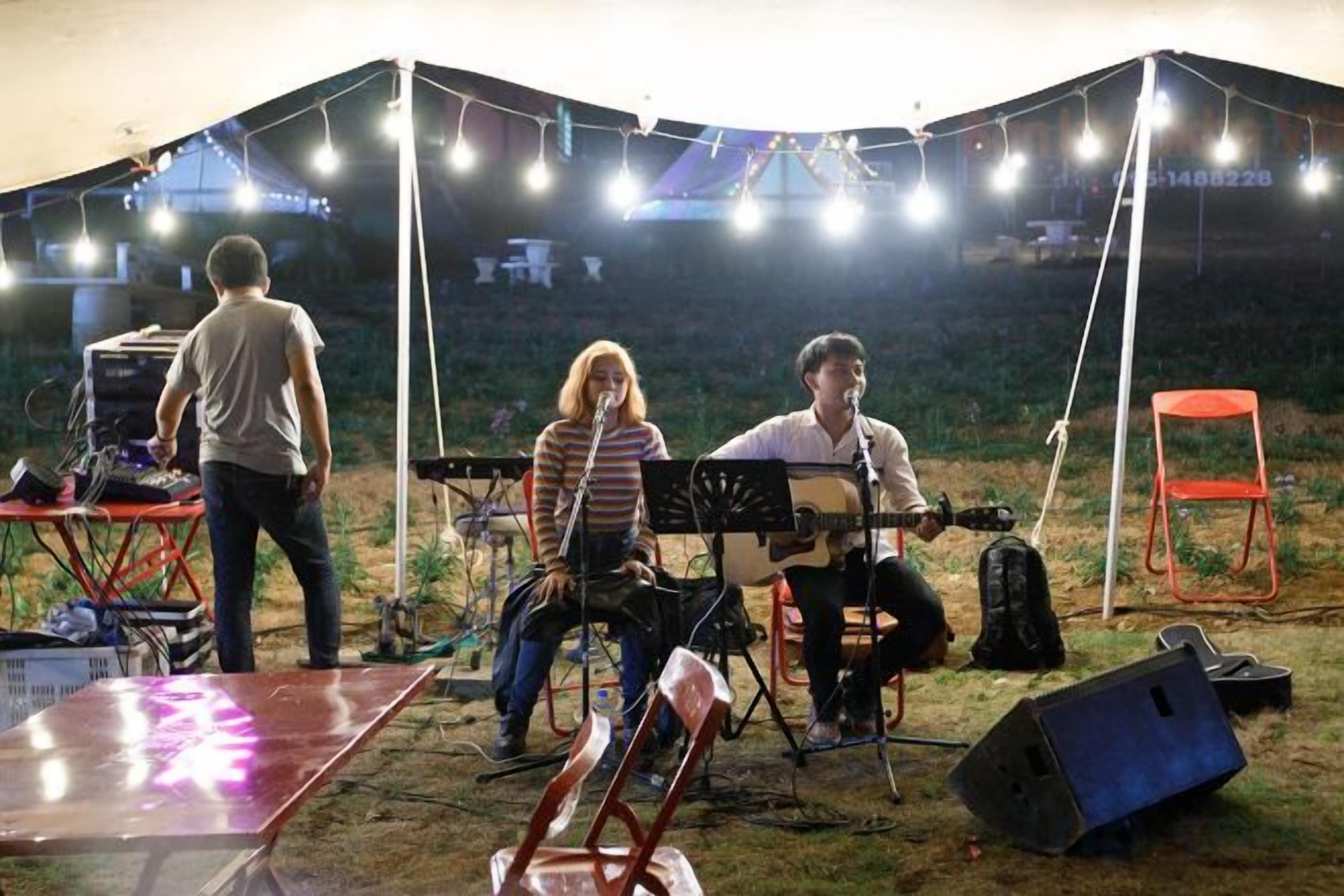 Montaje musical al aire libre con una tienda de campaña, sillas e instrumentos.