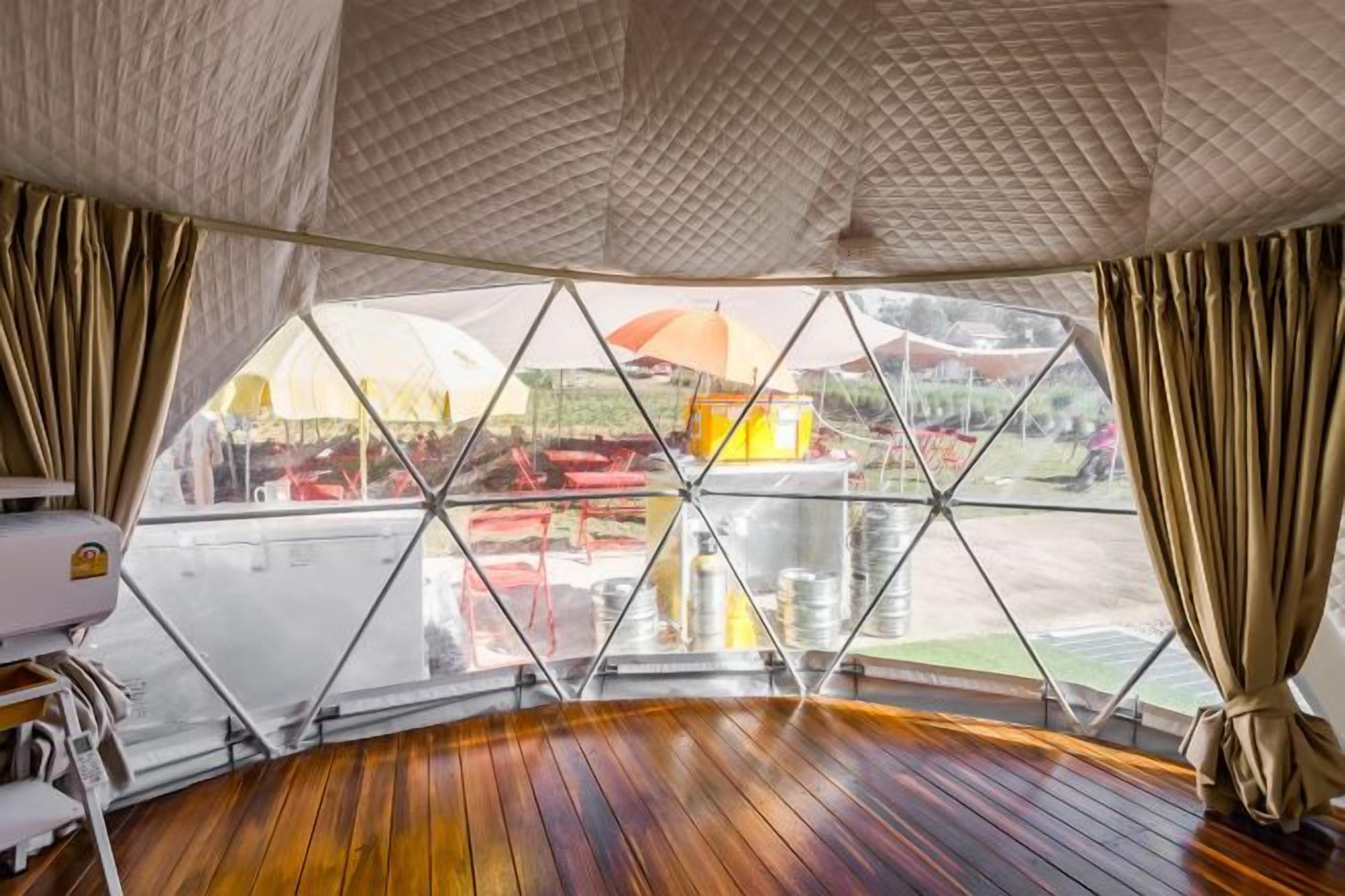 Quarto com piso de madeira, uma janela ampla com vista para o exterior e teto com padrão texturizado.