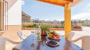 An outdoor patio with a wooden table set for two, featuring a bottle of white wine, glasses, and a plate of fruit. - La Antigua Fábrica Teba by Ruralidays (Málaga)