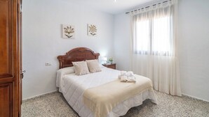 A neatly made bed with a wooden headboard, a bedside table with a lamp, and a window with sheer curtains. - La Antigua Fábrica Teba by Ruralidays (Málaga)