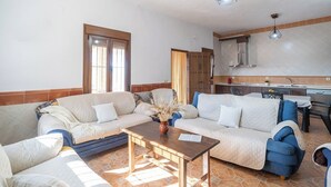 A living room with a sofa set, a coffee table, and a kitchen area in the background. - La Antigua Fábrica Teba by Ruralidays (Málaga)