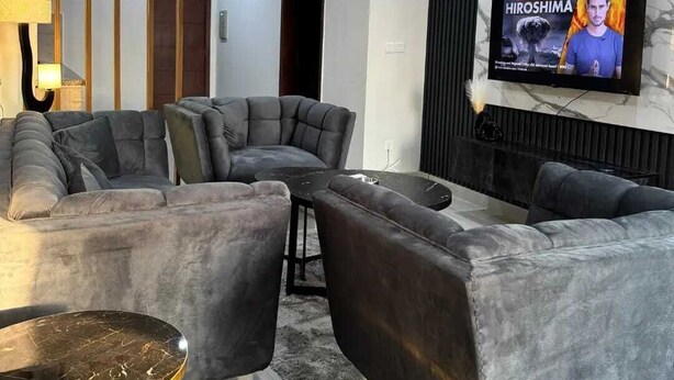 A modern living room with a sectional sofa, a coffee table, and a flat-screen TV mounted on the wall. - frnish flat  (Islamabad)