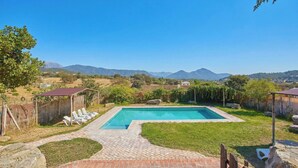 Une piscine rectangulaire bordée de briques, entourée d’une pelouse verdoyante et d’une terrasse en bois.