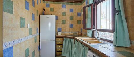 A compact kitchen with a refrigerator, sink, and washing machine.