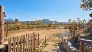 A rural landscape with a dirt path leading to a wooden gate, surrounded by vegetation and a basketball hoop. - Casa Los Olivos Prado del Rey by Ruralidays (Cádiz)