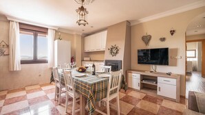 A dining area with a checkered floor, a table set for four, and a television on a stand. - Villa Cuesta Colorada Huétor Santillán by Ruralidays (Granada)