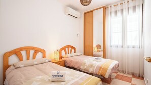 A hotel room with two wooden beds, a nightstand with a lamp, a large mirror, and a window with sheer curtains. - Villa Cuesta Colorada Huétor Santillán by Ruralidays (Granada)