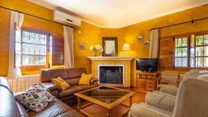 A cozy living room with a fireplace, leather sofa, and a television. - La Colina Villanueva del Rosario by Ruralidays (Málaga)