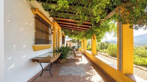 Un espace extérieur abrité, aménagé avec une pergola, un banc et une table.