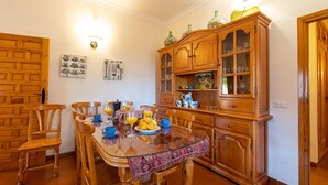 A dining area with a wooden table set for breakfast, surrounded by wooden chairs. - La Colina Villanueva del Rosario by Ruralidays (Málaga)