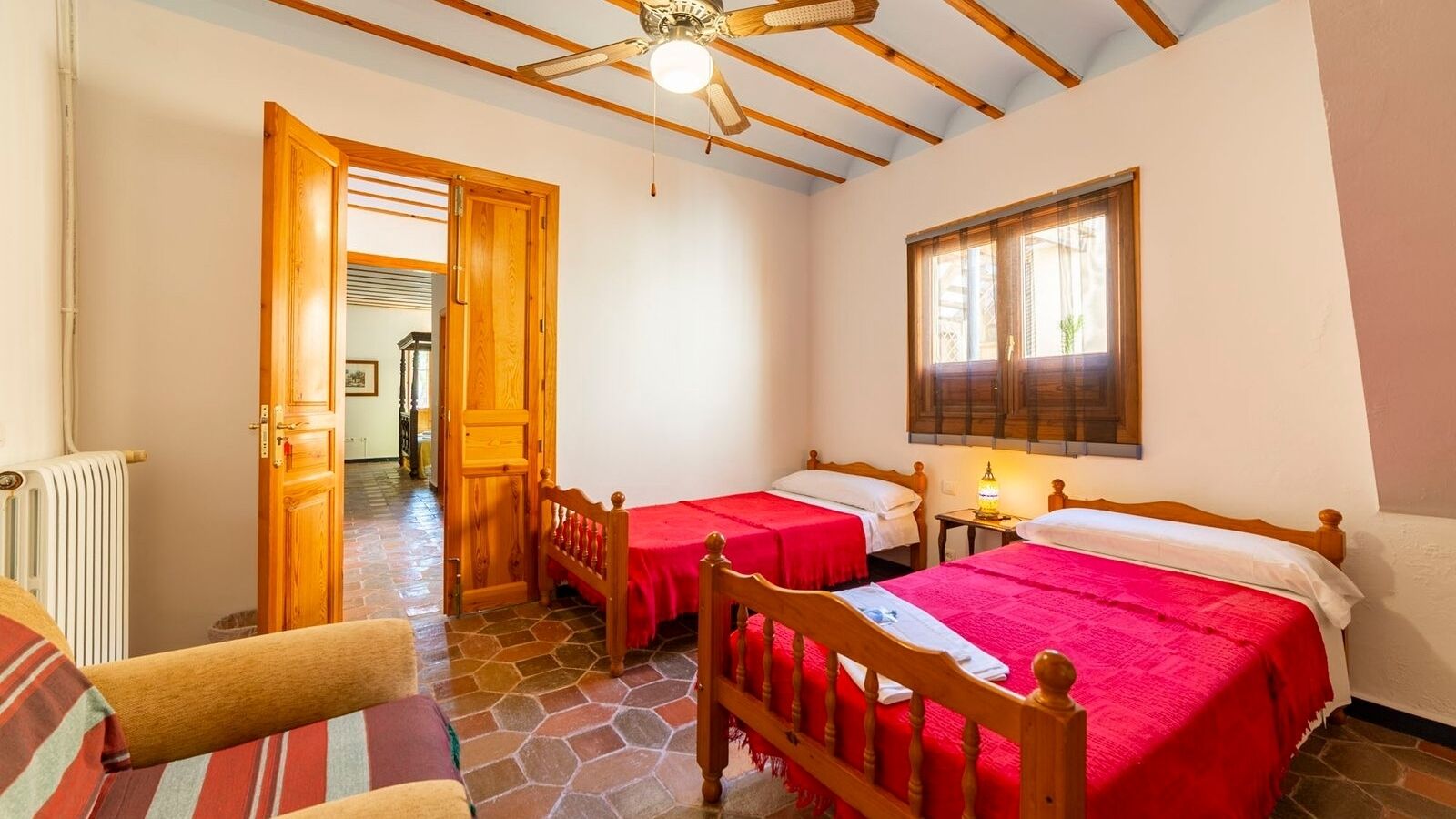 Une pièce confortable avec deux lits, un plafond en bois, un radiateur et une fenêtre avec des rideaux.