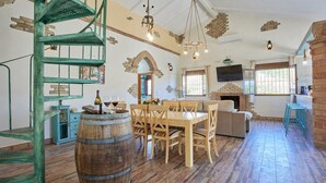A rustic interior with a wooden dining table, chairs, a barrel, a staircase, a fireplace, and a TV. - El Rincón de Marco y María Prado del Rey by Ruralidays (Cádiz)