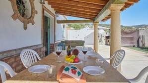 An outdoor dining area with a table set for two, a fruit bowl, wine glasses, and a bottle. - El Rincón de Marco y María Prado del Rey by Ruralidays (Cádiz)