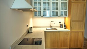 Una cocina compacta con horno integrado, un lavamanos y armarios de madera.