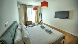 Una habitación de hotel moderna con una cama, dos lámparas colgantes rojas, un televisor de pantalla plana y un suelo a cuadros.