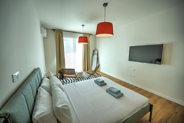 Una habitación de hotel moderna con una cama, dos lámparas colgantes rojas, un televisor de pantalla plana y un suelo a cuadros.