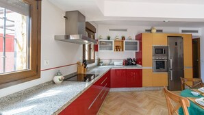 A modern kitchen with a stainless steel range hood, built-in oven, and a refrigerator. - Villa Tinahones Álora by Ruralidays (Málaga)