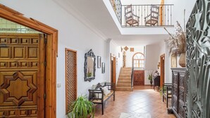 Um hall amplo com escada de madeira, um banco e um espelho decorativo.