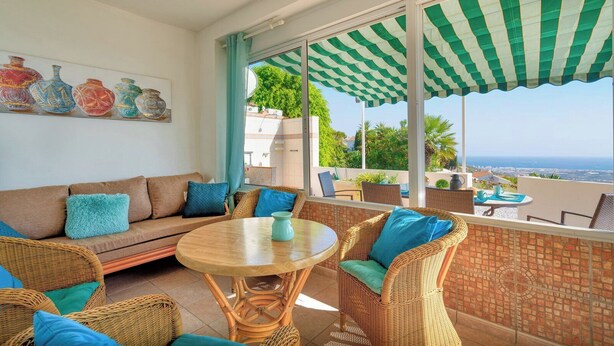 A sunlit patio with wicker furniture, a round table, and a view of the sea. - Casa La Paz - TRCP115 Torrox by Ruralidays (Málaga)