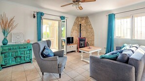 A living room with a stone wall, a television, a fireplace, a sofa, and a coffee table. - Casa La Paz - TRCP115 Torrox by Ruralidays (Málaga)